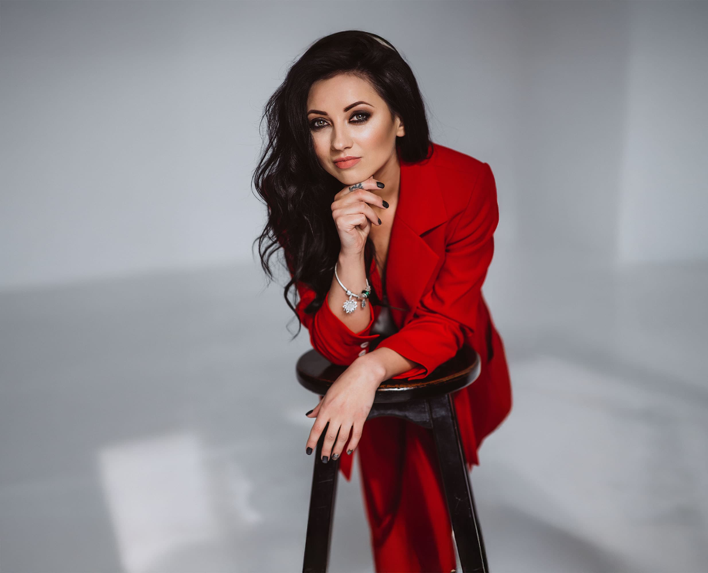Confident woman wearing a bold red suit, seated and looking directly at the camera — Dauntless 1-on-1 executive coaching